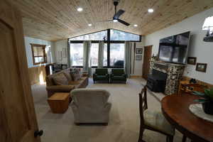 Living area featuring carpet, lofted ceiling, wooden ceiling, plenty of natural light, and wood walls