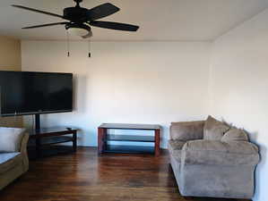 Living room featuring dark wood-type flooring and a ceiling fan