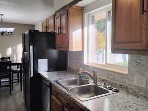 Kitchen with tasteful backsplash, a chandelier, light countertops, decorative light fixtures, and stainless steel dishwasher