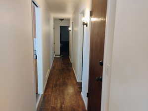 Hallway featuring dark wood-style flooring and baseboards