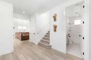 Staircase with plenty of natural light, wood finished floors, and recessed lighting