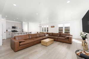 Living area with light wood-style flooring, recessed lighting, and a chandelier