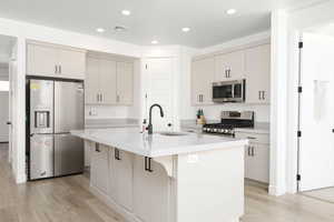 Kitchen with stainless steel appliances, an island with sink, light wood-type flooring, recessed lighting, and a kitchen breakfast bar