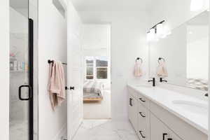 Ensuite bathroom with double vanity, light marble finish floors, and a marble finish shower