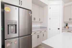 Kitchen with stainless steel fridge and white cabinetry