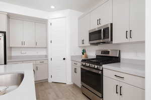 Kitchen featuring appliances with stainless steel finishes, light wood-type flooring, recessed lighting, and white cabinets