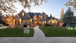 French country inspired facade featuring stone siding and a yard