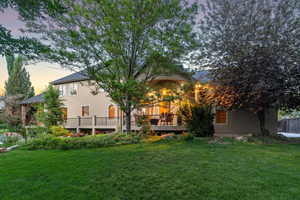 Back of house featuring a wooden deck, a yard, and stucco siding