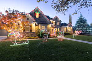 View of front of house featuring stone siding, a lawn, and stucco siding
