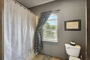Bathroom with curtained shower and tile patterned floors