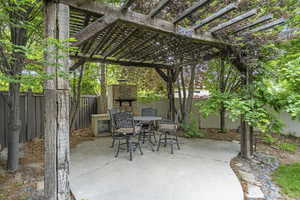 Fenced backyard featuring an outdoor stone fireplace, a patio area, outdoor dining space, and a pergola