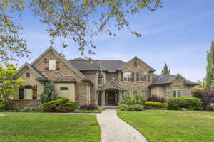 French country home with stone siding, a front lawn, and stucco siding