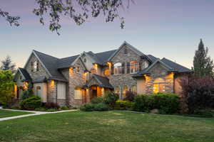 French country home featuring stone siding, a front yard, and stucco siding