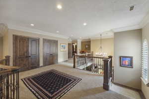 Foyer entrance with recessed lighting, ornamental molding, a chandelier, light colored carpet, and a textured ceiling