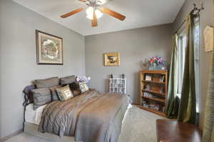 Carpeted bedroom with ceiling fan and baseboards