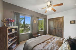 Bedroom with light colored carpet, a closet, and ceiling fan