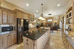 Kitchen with appliances with stainless steel finishes, dark stone counters, open floor plan, stone tile floors, and recessed lighting