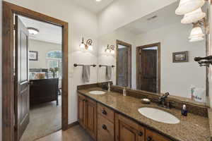 Bathroom with double vanity, dark tile patterned floors, and dark colored carpet