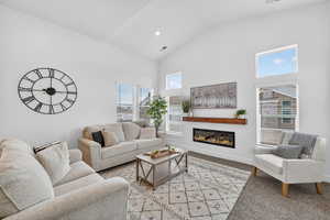 Living room featuring a glass covered fireplace, vaulted ceiling, recessed lighting.