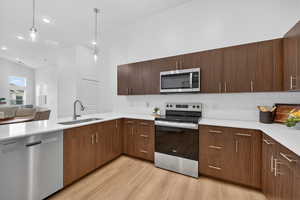 Kitchen featuring dark wood finish cabinets, a peninsula, modern cabinets, stainless steel appliances, and decorative pendent lights.