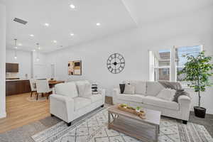 Living room featuring a glass covered fireplace, vaulted ceiling, recessed lighting.