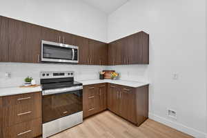 Kitchen featuring dark wood finish cabinets, a peninsula, modern cabinets, stainless steel appliances, and decorative pendent lights.