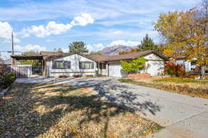Ranch-style home with concrete driveway, a mountain view, and a gate