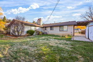 Rear view of house with a yard, a chimney, and brick siding
