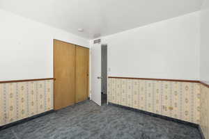 Carpeted spare room with wallpapered walls