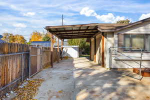 View of car parking with an attached carport, concrete driveway, and a storage unit