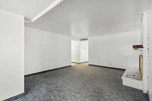 Unfurnished living room with a fireplace and dark carpet