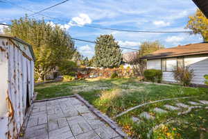 View of grassy yard with a patio area