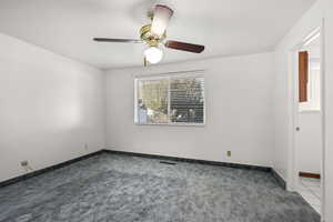 Carpeted spare room with a ceiling fan and baseboards