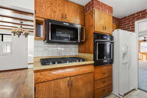 Kitchen featuring brown cabinetry, healthy amount of natural light, light countertops, and black appliances