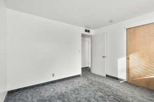 Spare room with dark carpet and baseboards