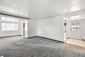 Unfurnished living room with light carpet and light tile patterned flooring