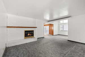 Unfurnished living room with carpet floors and a brick fireplace
