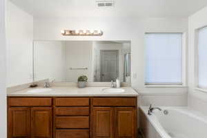 Full bath featuring double vanity and a bath