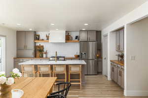 Kitchen with gray cabinetry, stainless steel appliances, light wood finished floors and a center island perfect for entertaining