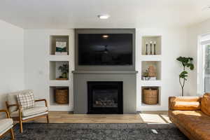 Living room with built in features, stylish upgrades and wood finished floors