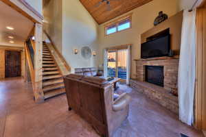 Living area with high vaulted ceiling, wood ceiling, a fireplace, stairs, and ceiling fan