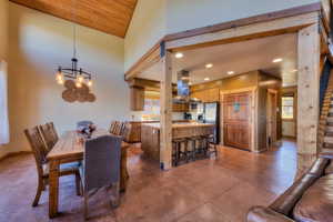 Dining space featuring recessed lighting, finished concrete flooring, high vaulted ceiling, a chandelier, and wood ceiling