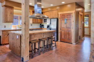 Kitchen featuring island exhaust hood, healthy amount of natural light, stainless steel appliances, finished concrete flooring, and recessed lighting