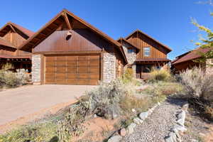 View of front of home featuring stone siding, an attached garage, and driveway