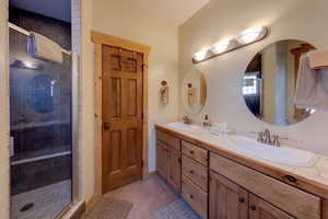 Bathroom featuring double vanity, a stall shower, and light tile patterned floors