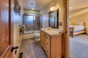 Ensuite bathroom with vanity, bath / shower combo with glass door, and dark tile patterned flooring