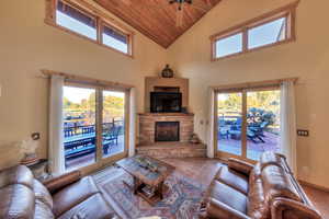 Tiled living area with wooden ceiling, high vaulted ceiling, a fireplace, plenty of natural light, and a ceiling fan