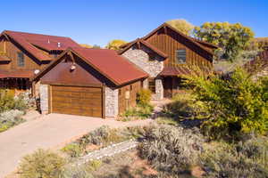 View of front of property featuring stone siding, driveway, board and batten siding, and an attached garage