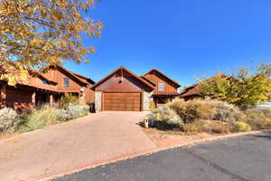 View of front of home featuring stone siding, driveway, a garage, and board and batten siding