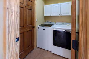 Laundry area with cabinet space, washer and clothes dryer, and light tile patterned floors